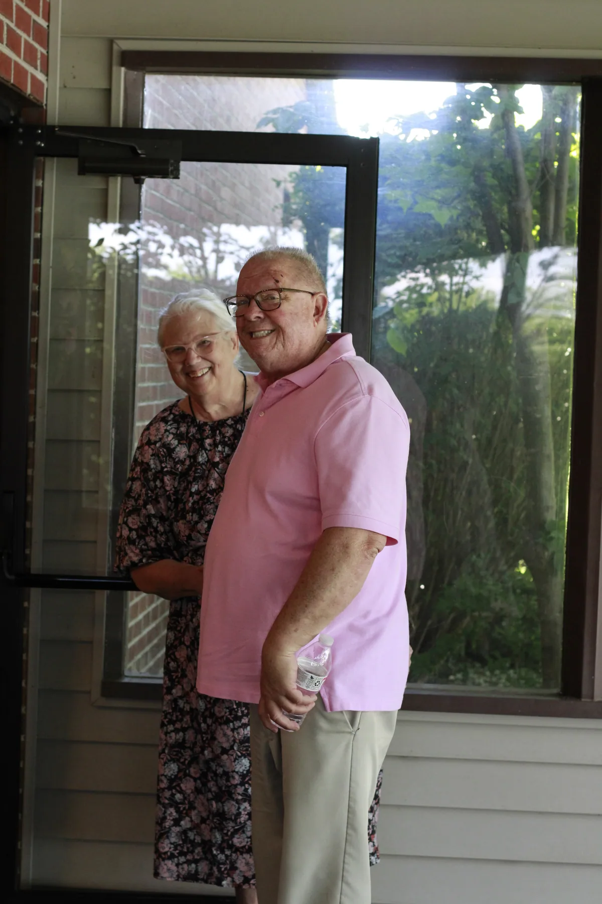 Two smiling members welcoming people at Bethel’s front door