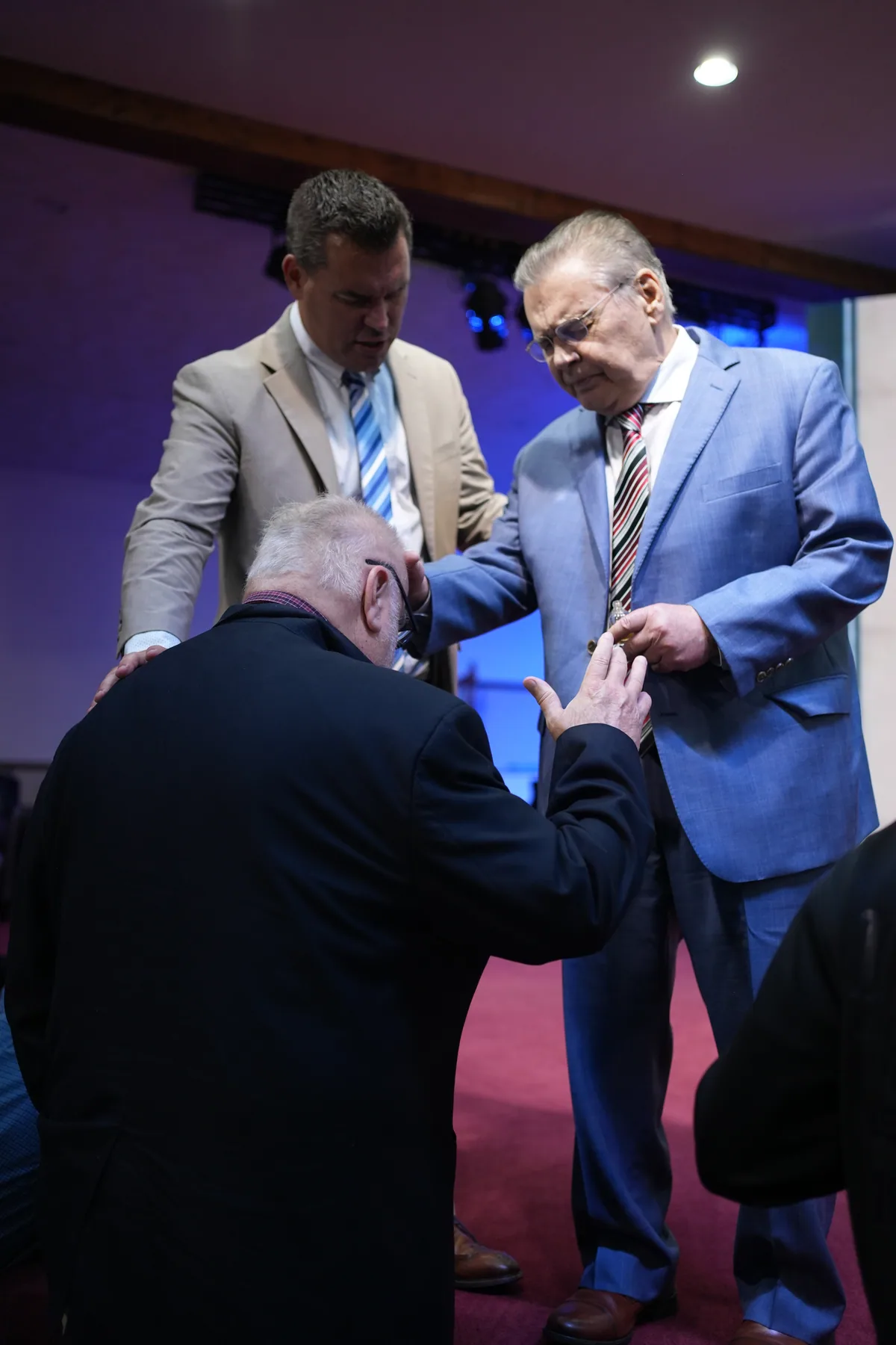 Men praying together over a brother at the altar